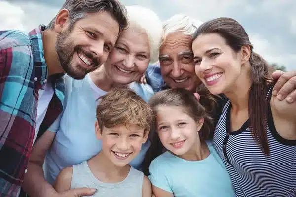 Groupe de six personnes souriantes, générations mêlées, lors d’un moment convivial en extérieur, représentant le bien-être et l’harmonie autour du sujet les bienfaits du magnétisme sur la santé.