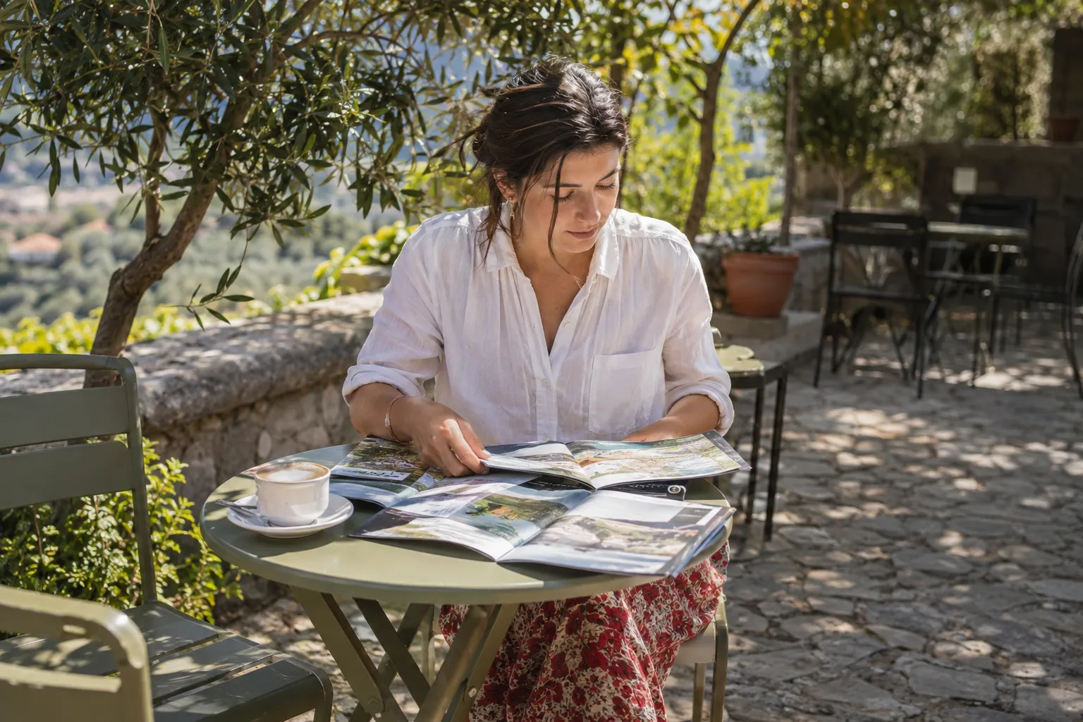 Intelligence transgénérationnelle et blessures du passé 3 Une femme lit un magazine assise à une table extérieure sur un patio.